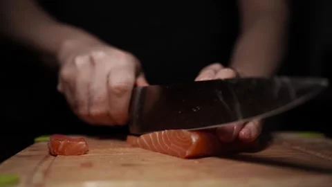 Close-Up of Hands Slicing Fresh Salmon Fillet on a Dark Background Видео 303898696