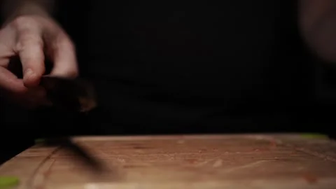 Close-Up of Hands Slicing Fresh Salmon Fillet on a Dark Background Stock Footage 303898713