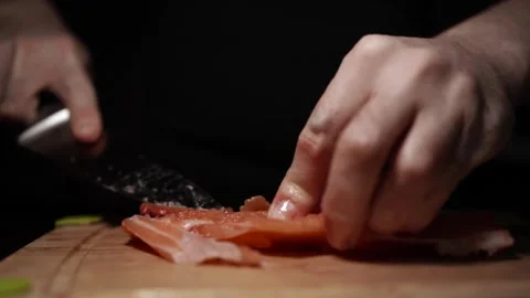 Close-Up of Hands Slicing Fresh Salmon Fillet on a Dark Background 스톡 동영상 303898730