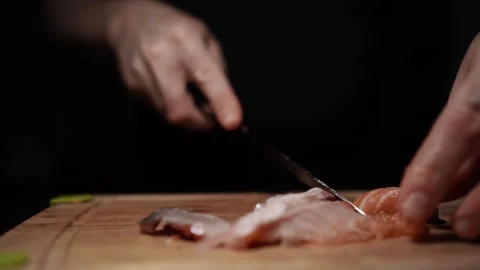 Close-Up of Hands Slicing Fresh Salmon Fillet on a Dark Background Stockbeeldmateriaal 303898736