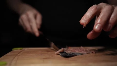 Close-Up of Hands Slicing Fresh Salmon Fillet on a Dark Background Stock Footage 303898737