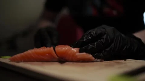 Close-Up of Hands Slicing Fresh Salmon Fillet on a Dark Background Video stock 303898955