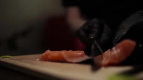 Close-Up of Hands Slicing Fresh Salmon Fillet on a Dark Background Видео 303898972