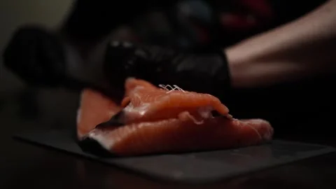Close-Up of Hands Slicing Fresh Salmon Fillet on a Dark Background 스톡 동영상 303898996