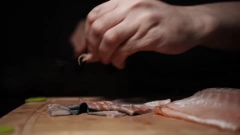 Close-Up of Hands Slicing Fresh Salmon Fillet on a Dark Background Stockbeeldmateriaal 303900791