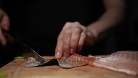 Close-Up of Hands Slicing Fresh Salmon Fillet on a Dark Background Stock Footage 303900804