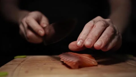 Close-Up of Hands Slicing Fresh Salmon Fillet on a Dark Background 스톡 동영상 303900843