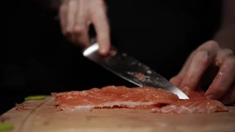Close-Up of Hands Slicing Fresh Salmon Fillet on a Dark Background 스톡 동영상 303900855