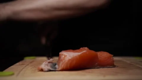 Close-Up of Hands Slicing Fresh Salmon Fillet on a Dark Background 스톡 동영상 303901389