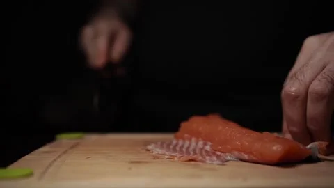 Close-Up of Hands Slicing Fresh Salmon Fillet on a Dark Background Stock Footage 303901429
