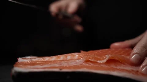 Close-Up of Hands Slicing Fresh Salmon Fillet on a Dark Background 스톡 동영상 303901562