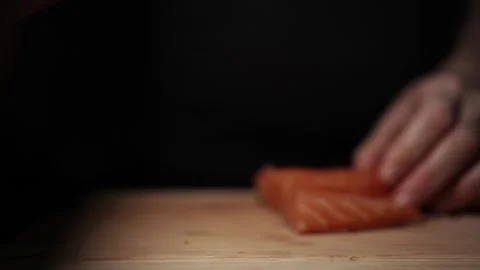 Close-Up of Hands Slicing Fresh Salmon Fillet on a Dark Background Video stock 303901564