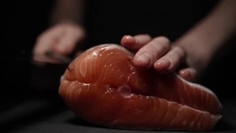 Close-Up of Hands Slicing Fresh Salmon Fillet on a Dark Background Stock Footage 303901596