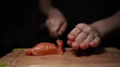 Close-Up of Hands Slicing Fresh Salmon Fillet on a Dark Background Stock Footage 303901622