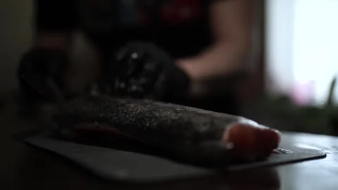 Close-Up of Hands Slicing Fresh Salmon Fillet on a Dark Background Video stock 303901699