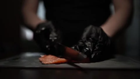 Close-Up of Hands Slicing Fresh Salmon Fillet on a Dark Background Video stock 303901701