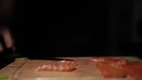 Close-Up of Hands Slicing Fresh Salmon Fillet on a Dark Background Stock-Footage 303901997