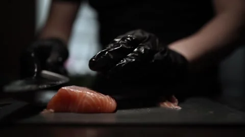 Close-Up of Hands Slicing Fresh Salmon Fillet on a Dark Background Stock Footage 303903230