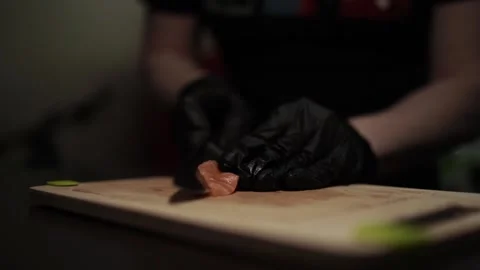 Close-Up of Hands Slicing Fresh Salmon Fillet on a Dark Background Видео 303903607