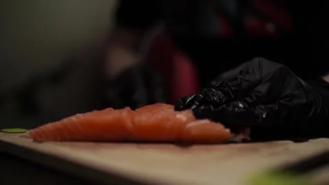 Close-Up of Hands Slicing Fresh Salmon Fillet on a Dark Background Video stock 303903642