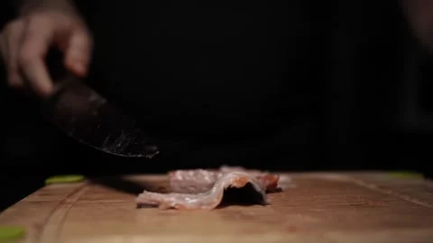 Close-Up of Hands Slicing Fresh Salmon Fillet on a Dark Background Video stock 303906079