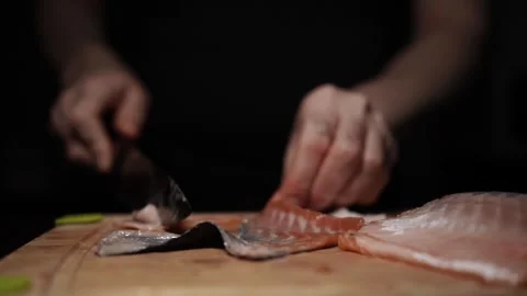 Close-Up of Hands Slicing Fresh Salmon Fillet on a Dark Background Stock Footage 303906117