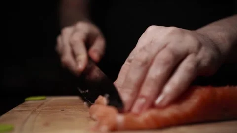 Close-Up of Hands Slicing Fresh Salmon Fillet on a Dark Background 스톡 동영상 303906147