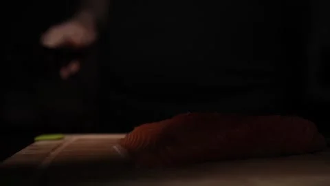 Close-Up of Hands Slicing Fresh Salmon Fillet on a Dark Background Stock-Footage 303906154