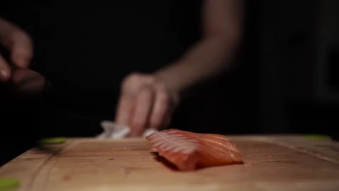 Close-Up of Hands Slicing Fresh Salmon Fillet on a Dark Background 스톡 동영상 303906159