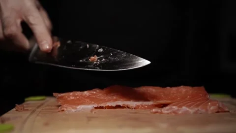 Close-Up of Hands Slicing Fresh Salmon Fillet on a Dark Background Stock Footage 303906182