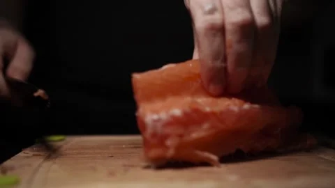 Close-Up of Hands Slicing Fresh Salmon Fillet on a Dark Background Видео 303906183