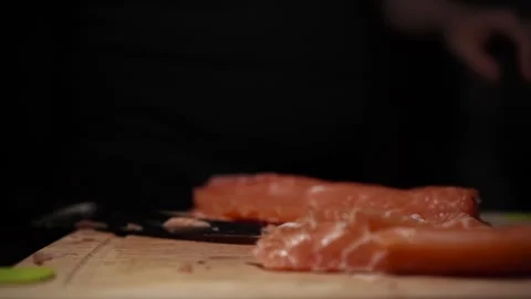 Close-Up of Hands Slicing Fresh Salmon Fillet on a Dark Background Video stock 303906198