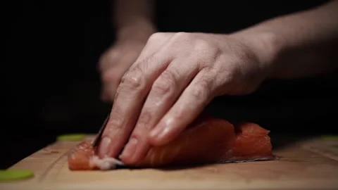 Close-Up of Hands Slicing Fresh Salmon Fillet on a Dark Background 스톡 동영상 303906210