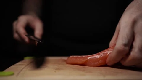 Close-Up of Hands Slicing Fresh Salmon Fillet on a Dark Background Vídeos de archivo 303906226
