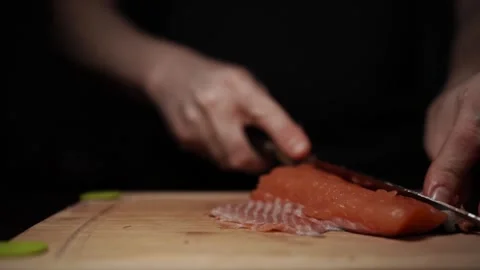Close-Up of Hands Slicing Fresh Salmon Fillet on a Dark Background Stock Footage 303906227