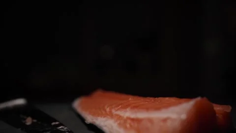 Close-Up of Hands Slicing Fresh Salmon Fillet on a Dark Background 스톡 동영상 303906233