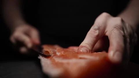 Close-Up of Hands Slicing Fresh Salmon Fillet on a Dark Background Stock-Footage 303906252