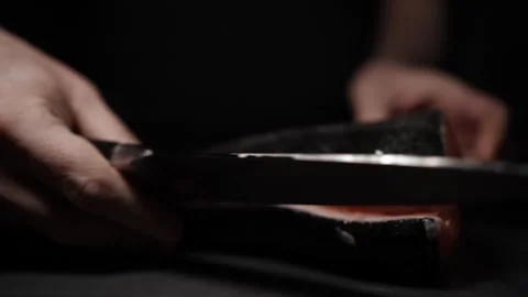 Close-Up of Hands Slicing Fresh Salmon Fillet on a Dark Background Видео 303906279