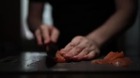Close-Up of Hands Slicing Fresh Salmon Fillet on a Dark Background Stock Footage 303906325
