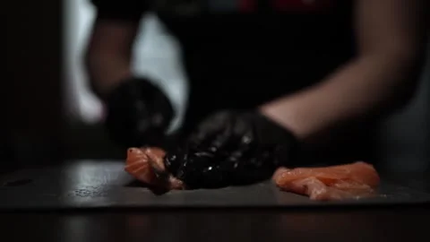 Close-Up of Hands Slicing Fresh Salmon Fillet on a Dark Background 스톡 동영상 303906345