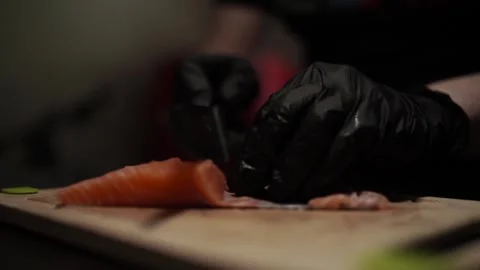 Close-Up of Hands Slicing Fresh Salmon Fillet on a Dark Background Video stock 303906357
