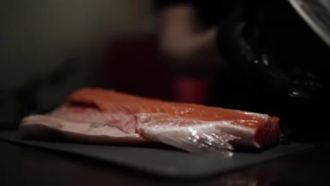 Close-Up of Hands Slicing Fresh Salmon Fillet on a Dark Background Stock Footage 303906372