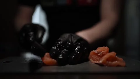 Close-Up of Hands Slicing Fresh Salmon Fillet on a Dark Background Video stock 303907089