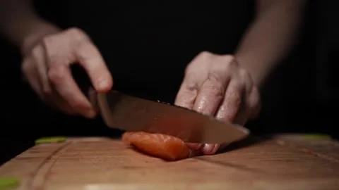 Close-Up of Hands Slicing Fresh Salmon Fillet on a Dark Background Stock Footage 303907363
