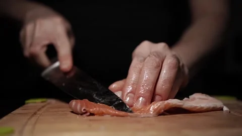 Close-Up of Hands Slicing Fresh Salmon Fillet on a Dark Background Stock Footage 303908029