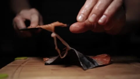 Close-Up of Hands Slicing Fresh Salmon Fillet on a Dark Background Stock Footage 303908032