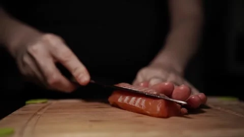Close-Up of Hands Slicing Fresh Salmon Fillet on a Dark Background Stock Footage 303908045