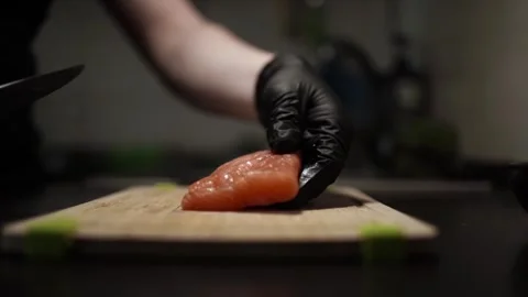 Close-Up of Hands Slicing Fresh Salmon Fillet on a Dark Background Stock-Footage 303908137