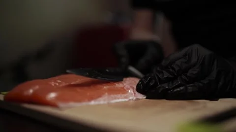 Close-Up of Hands Slicing Fresh Salmon Fillet on a Dark Background Vídeos de archivo 303908167