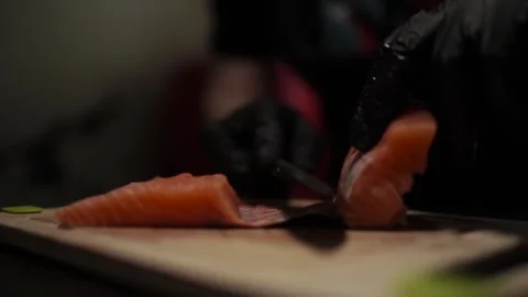 Close-Up of Hands Slicing Fresh Salmon Fillet on a Dark Background Stock Footage 303908183